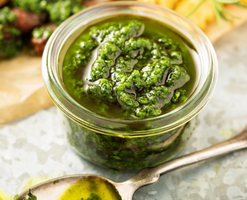 Easy Vegan Carrot Top Pesto Recipe 5 Closeup of carrot top pesto in a glass jar with a spoon resting next to it