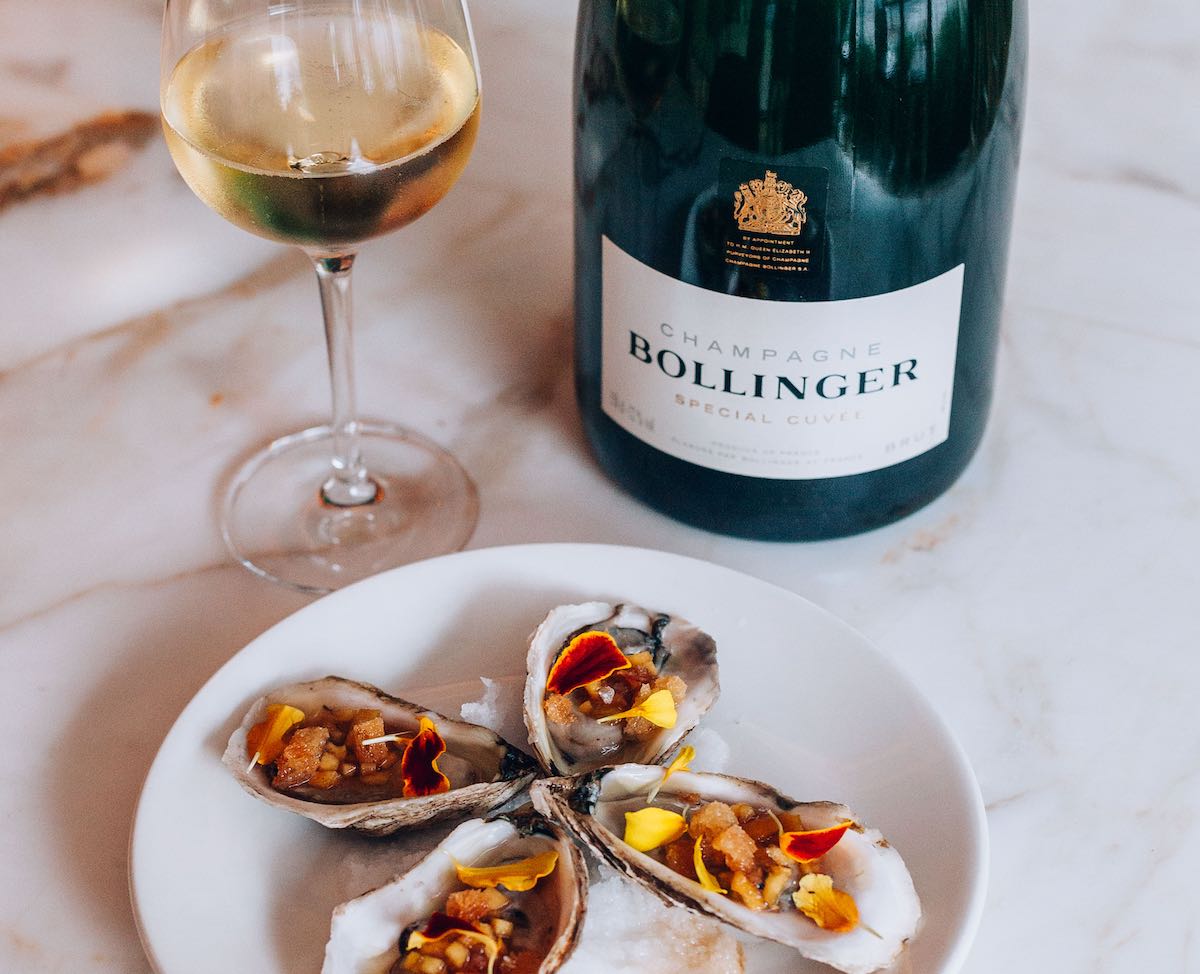 Bollinger Special Cuvee bottle on a white tablecloth with a plate of oysters