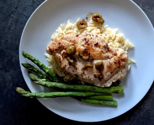 braised chicken breast with asparagus on a white plate