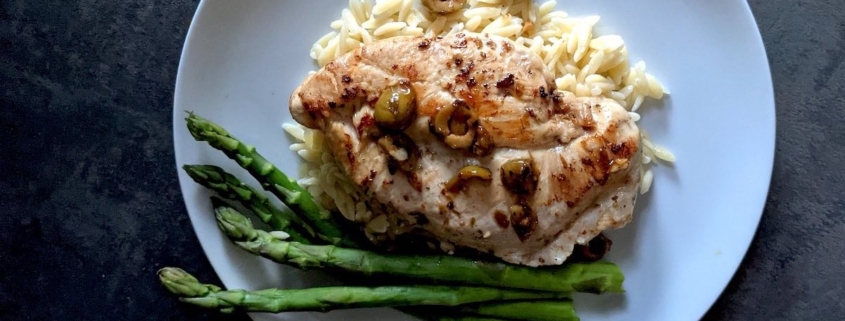 braised chicken breast with asparagus on a white plate