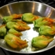 closeup of stuffed courgette flowers being cooked in a sauté pan