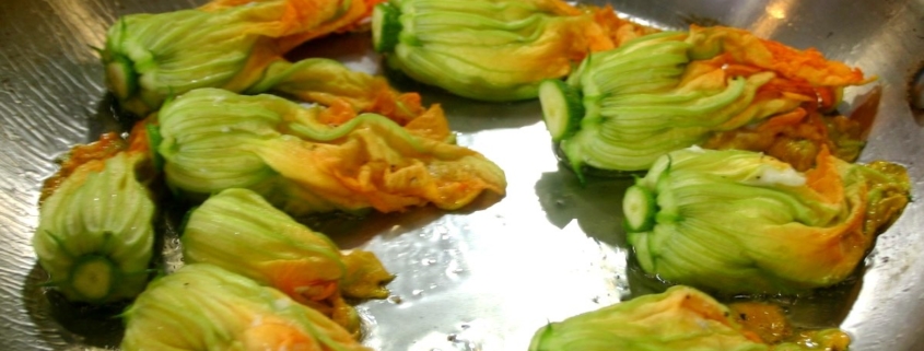 closeup of stuffed courgette flowers being cooked in a sauté pan