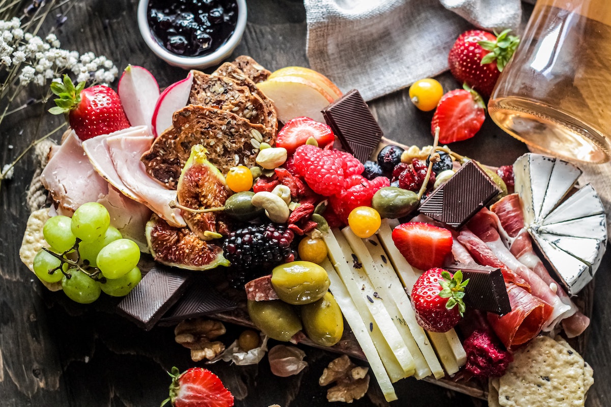 Colorful charcuterie board with a variety of fruits and flowers to illustrate using color and garnishes