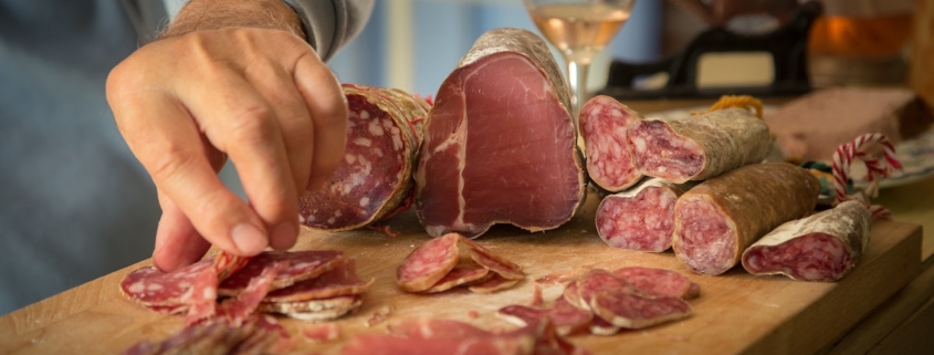 Charcuterie board with someone reaching to take a piece of meat