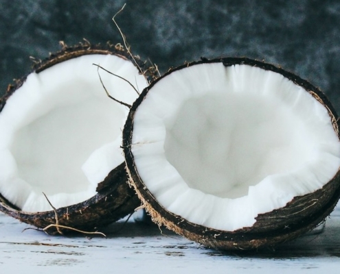two coconut halves on a white counter with a marbled dark blue background
