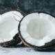 two coconut halves on a white counter with a marbled dark blue background