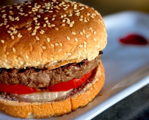 buffalo burger (bison burger) on a whole wheat bun on a white plate with a red heart