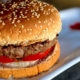 buffalo burger (bison burger) on a whole wheat bun on a white plate with a red heart