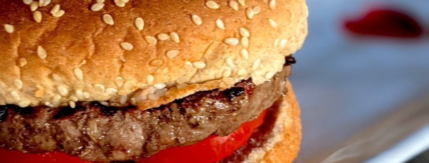 buffalo burger (bison burger) on a whole wheat bun on a white plate with a red heart