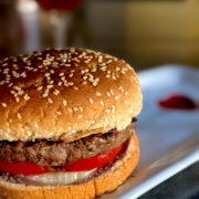 bison burger (buffalo burger) with a whole wheat bun on a white plate with a red heart