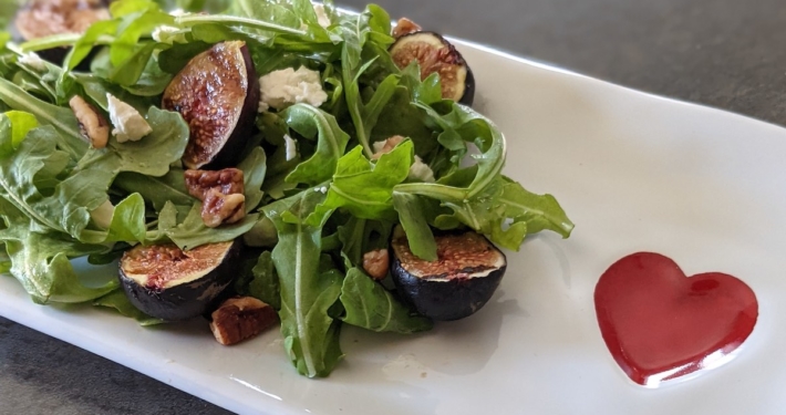 The Summer Salad That Makes Fresh Figs Impossible to Resist 1 grilled fig and arugula salad on a white plate with a red heart
