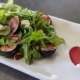 grilled fig and arugula salad on a white plate with a red heart