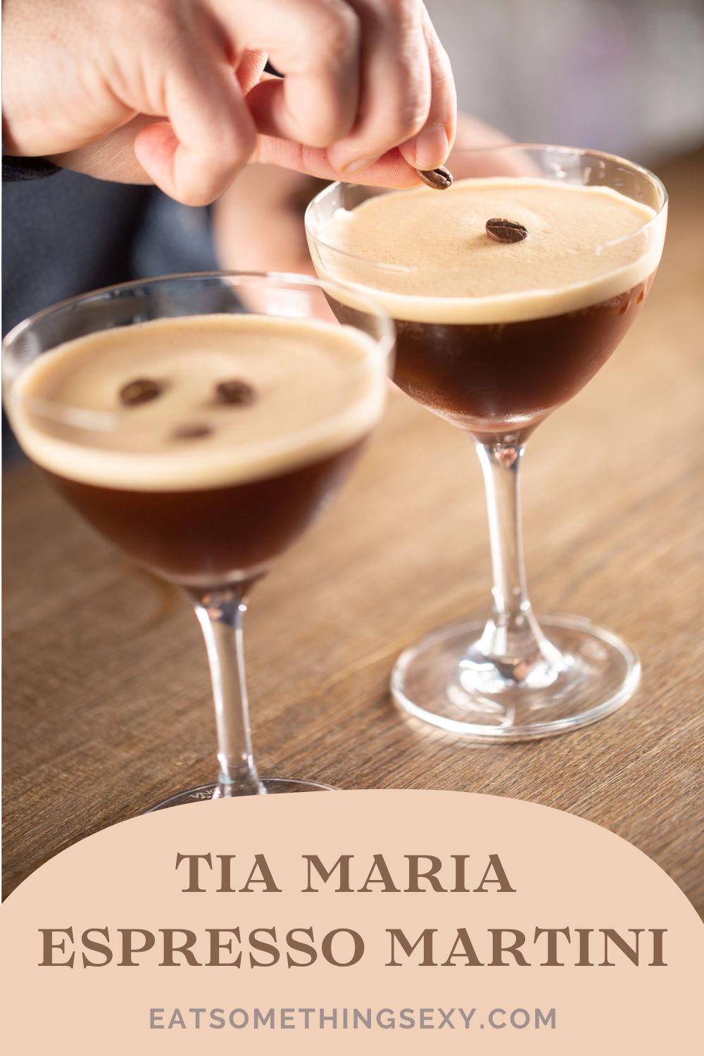 Tia Maria Espresso Martini Recipe 4 Tia Maria Cold Brew Espresso Martini graphic with a hand garnishing two martinis and text at the bottom reading, "tia maria espresso martini eatsomethingsexy.com"