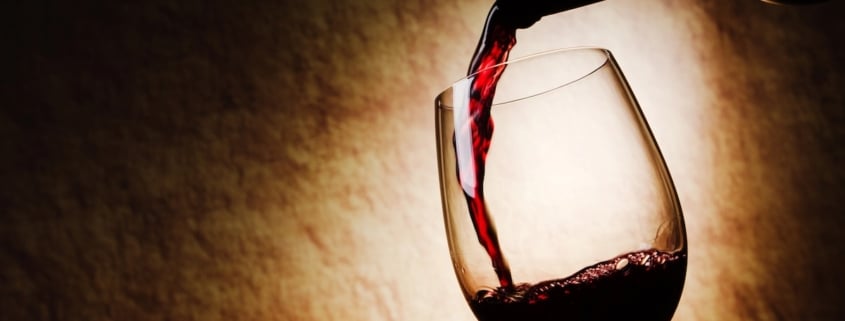 Wine and Men's Sexual Health 1 neck of a wine bottle with wine being poured into a stemmed glass on a spotlit, beige background