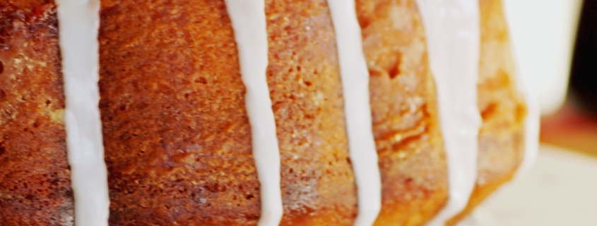 closeup of pumpkin bundt cake with a vanilla glaze on a white plate