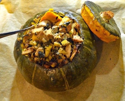 vegan stuffed kabocha squash on brown parchment with a silver serving spoon