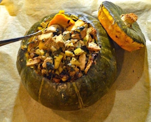 Roasted Stuffed Kabocha Squash Recipe 2 vegan stuffed kabocha squash on brown parchment with a silver serving spoon