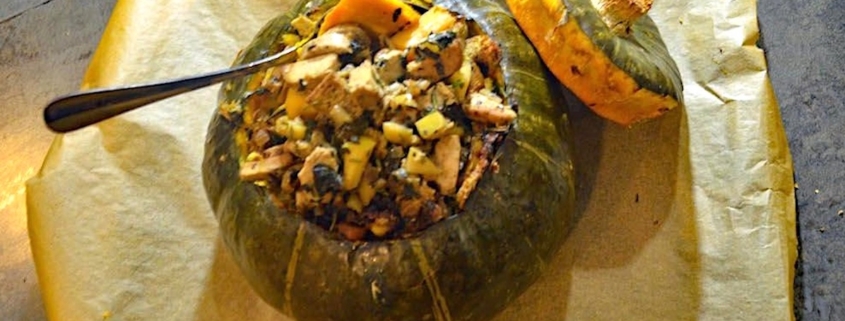 vegan stuffed kabocha squash on brown parchment with a silver serving spoon