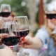 Closeup on the hands of several women toasting with glasses of red wine