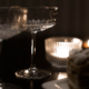Two champagne glasses on a dark table lit by candlelight to represent this romantic New Year's Eve dinner for two