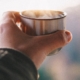 man's hand holding a copper cup of tea at sunrise