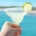 Woman's hand holding a margarita with a lime wheel garnish in front of a clear blue ocean