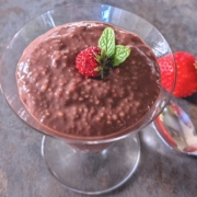 closeup of strawberry chia pudding in a parfait glass with a spoon and fresh strawberries on the side