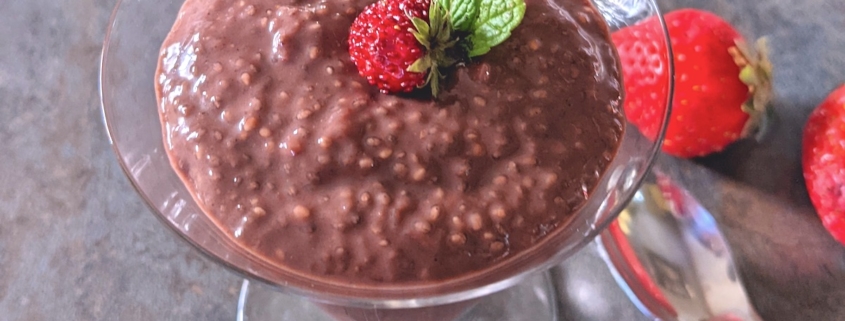 closeup of strawberry chia pudding in a parfait glass with a spoon and fresh strawberries on the side