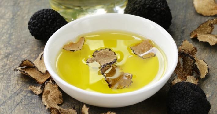 How to Choose the Best Truffle Oil (And Why Most Fall Short) 1 white bowl of oil with truffle pieces and truffles sitting beside the bowl