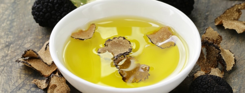 white bowl of oil with truffle pieces and truffles sitting beside the bowl