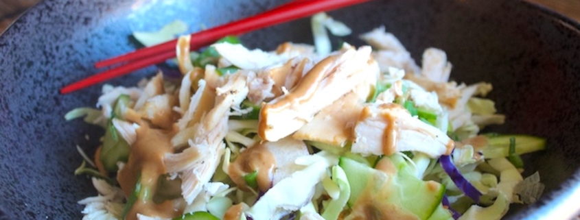 closeup of Asian chicken rice bowl in black pottery with red chopsticks on a bamboo placemat