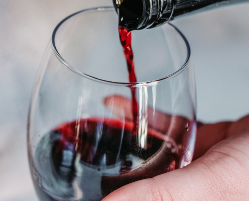 What is Malbec Wine? A Guide to the Everyday Red Wine 7 woman's hand holding a stemless wine glass while she pours Malbec wine into it from a dark bottle