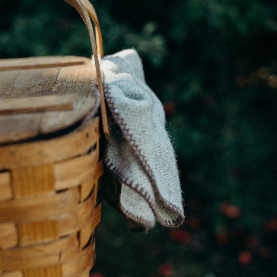 picnic basket with a soft, beige picnic blanket draped over the side