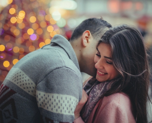 Couple embracing in front of a lit Christmas tree