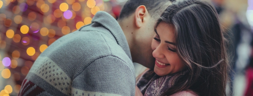 Couple embracing in front of a lit Christmas tree