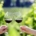 a man and woman's hands toasting with red wine glasses in a vineyard, the people are not visible