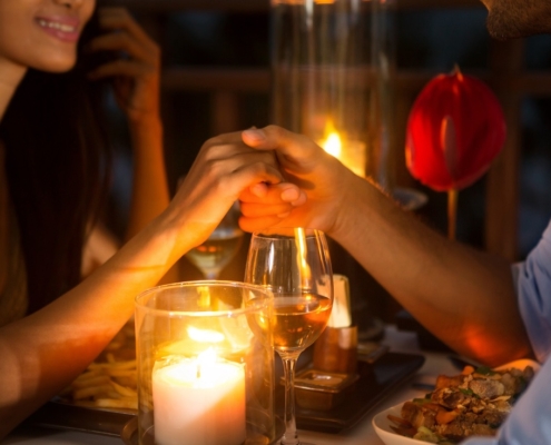 Couple holding hands at the dinner table lit by candlelight