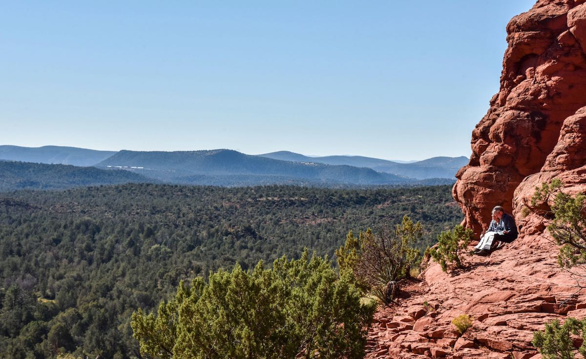 Couple resting on red rocks overlooking a valley