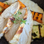 closeup of date night chicken with polenta and grilled vegetables in a black, stoneware bowl