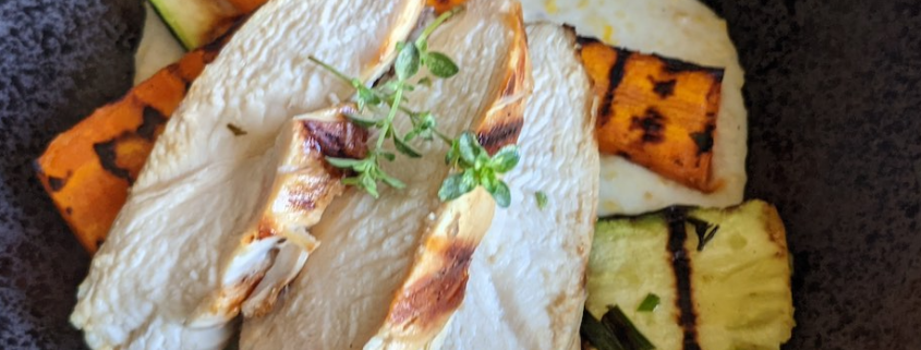 closeup of date night chicken with polenta and grilled vegetables in a black, stoneware bowl