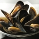 Closeup of spicy mussels on a small pot on a white background