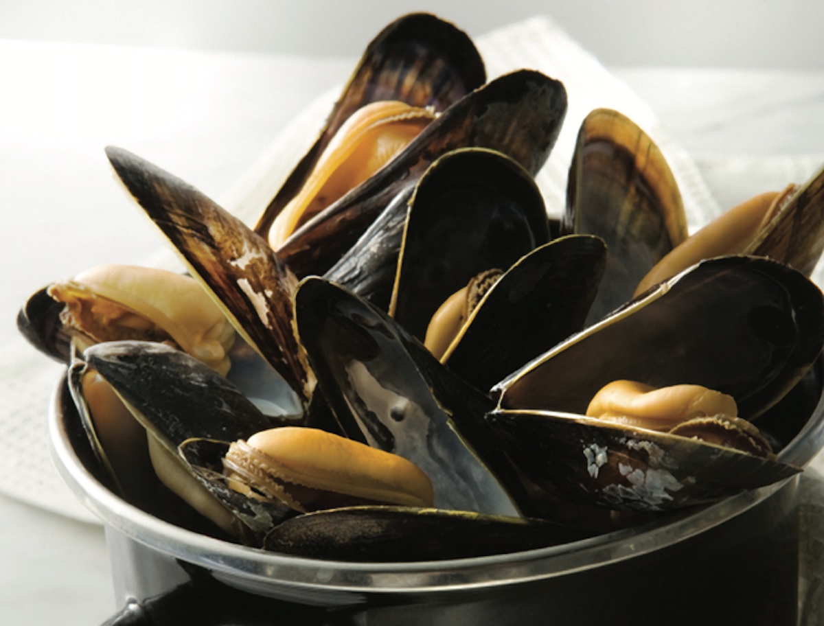 Closeup of spicy mussels on a small pot on a white background