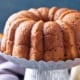 Homemade Pumpkin Bundt Cake With Pumpkin Pie Spice 21 closeup of a pumpkin bundt cake on a tin cake stand with two pumpkins in the background