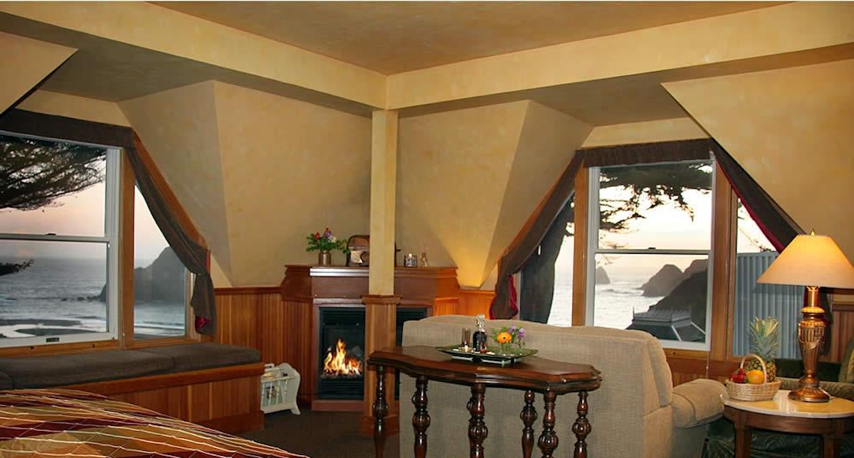 Elk Cove Inn Seascape room with fireplace in corner and two picture windows