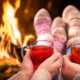 couple's hands holding sorrel hot toddy's in front of a roaring fire