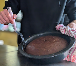 Woman using the Ashley Holt 4-inch offset spatula to remove a round chocolate cake from the pan