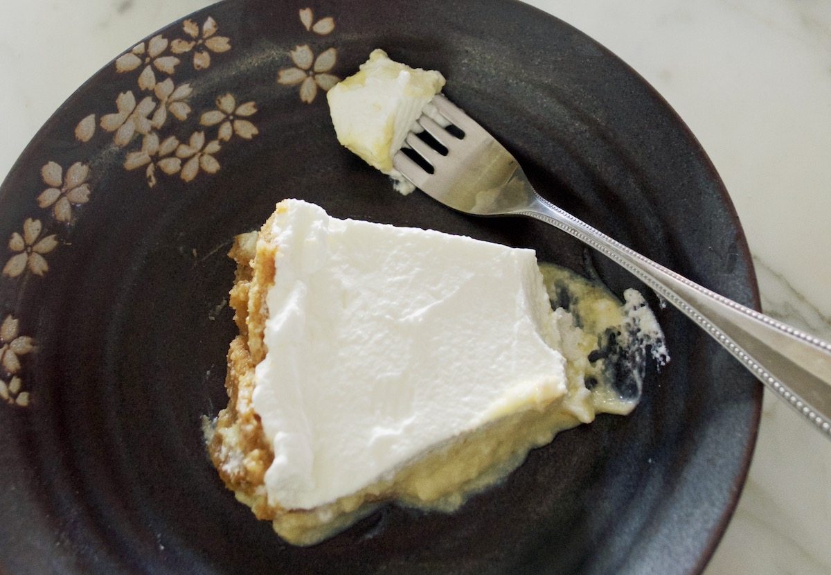 closeup of a slice of crazy sexy key lime pie on a black plate with a faint floral pattern and a silver fork above the slice