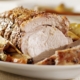 Closeup of oven roasted pork loin with vegetables on a white plate
