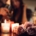 votive candles and a bouquet of roses in the foreground with the torsos of a couple snuggling and holding wine in the background