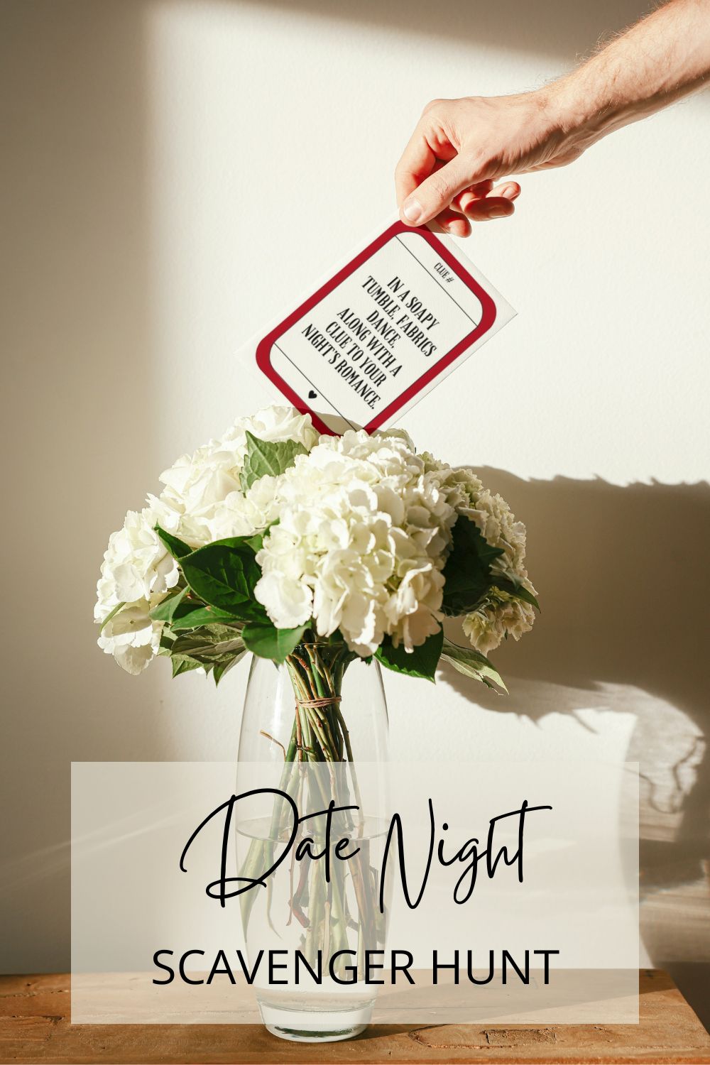 hand pulling sample date night scavenger hunt card out from behind a bouquet of flowers